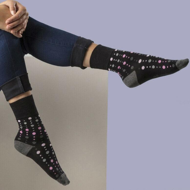 woman wearing black bamboo non binding socks with pick and white dots
